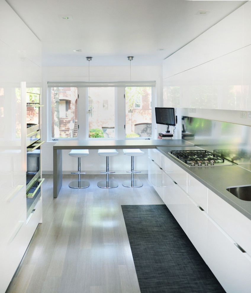 Medium sized contemporary l-shaped kitchen in DC Metro with flat-panel cabinets, white cabinets, a submerged sink, quartz worktops, metallic splashback, metal splashback, stainless steel appliances, light hardwood flooring and a breakfast bar.