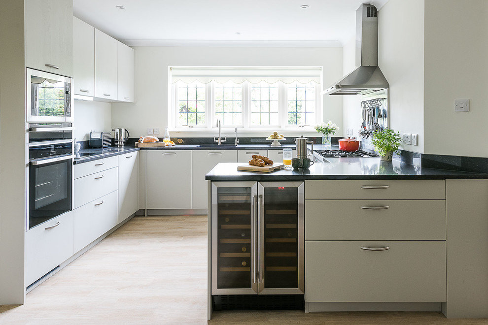 Inspiration for a contemporary u-shaped light wood floor kitchen remodel in London with an undermount sink, flat-panel cabinets, black backsplash, stainless steel appliances and a peninsula