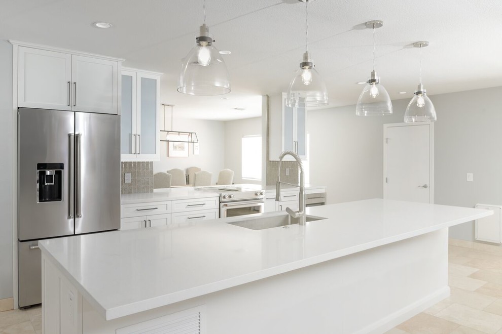 Modern inredning av ett mellanstort kök, med en undermonterad diskho, skåp i shakerstil, vita skåp, laminatbänkskiva, brunt stänkskydd, stänkskydd i glaskakel, rostfria vitvaror, travertin golv, en köksö och beiget golv