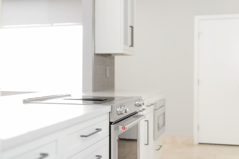 Esempio di una cucina minimal di medie dimensioni con lavello sottopiano, ante in stile shaker, ante bianche, top in laminato, paraspruzzi marrone, paraspruzzi con piastrelle di vetro, elettrodomestici in acciaio inossidabile, pavimento in travertino e pavimento beige