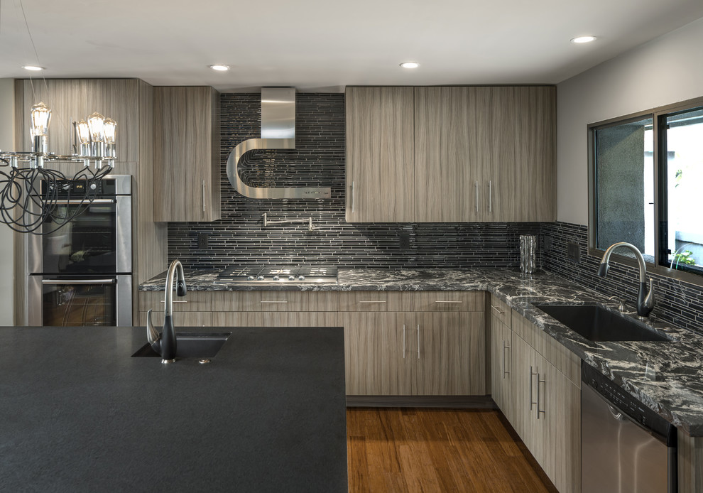 Large contemporary l-shaped open plan kitchen in Phoenix with a submerged sink, flat-panel cabinets, grey cabinets, granite worktops, black splashback, stainless steel appliances, bamboo flooring and an island.