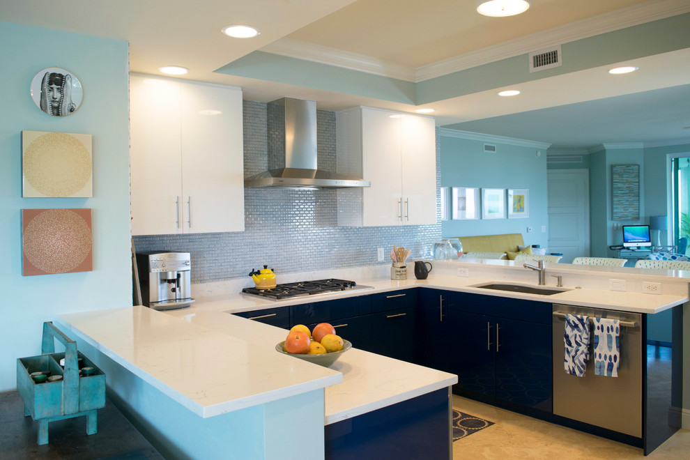 Inredning av ett modernt litet kök, med släta luckor, bänkskiva i kvarts, blått stänkskydd, rostfria vitvaror, en undermonterad diskho, blå skåp, stänkskydd i glaskakel, laminatgolv och beiget golv