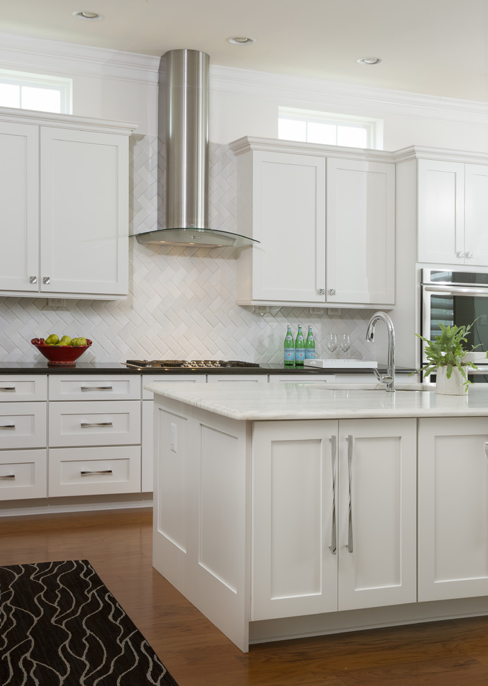 Inspiration for a large contemporary l-shaped dark wood floor eat-in kitchen remodel in Newark with a double-bowl sink, recessed-panel cabinets, white cabinets, marble countertops, white backsplash, mosaic tile backsplash, stainless steel appliances and an island