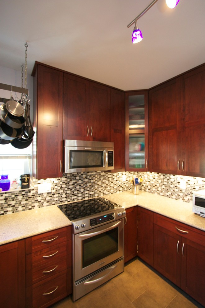 Foto på ett funkis u-kök, med skåp i shakerstil, skåp i mörkt trä, granitbänkskiva, flerfärgad stänkskydd, stänkskydd i glaskakel och rostfria vitvaror