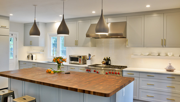 На фото: кухня в современном стиле с серыми фасадами, деревянной столешницей и островом