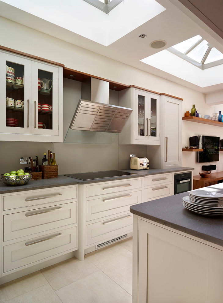 Inspiration for a medium sized contemporary l-shaped open plan kitchen in London with shaker cabinets, stainless steel appliances, an island, a built-in sink, grey cabinets, grey splashback, glass sheet splashback and limestone flooring.