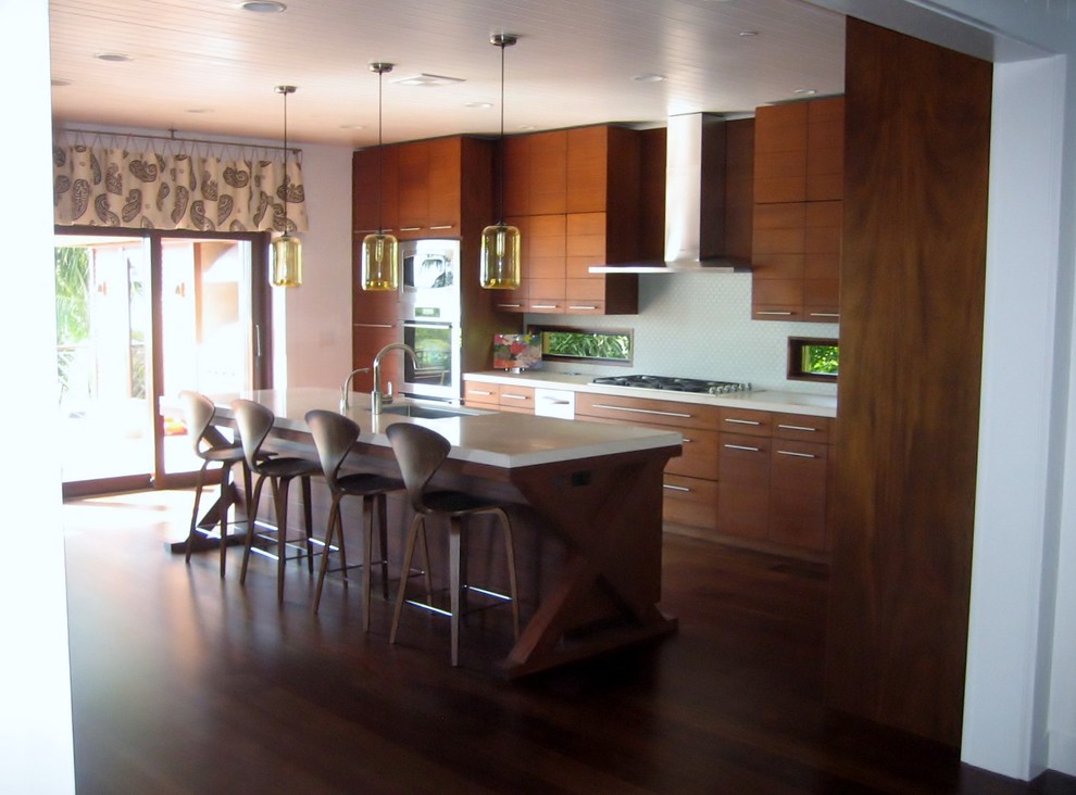 Cette image montre une cuisine ouverte parallèle minimaliste en bois brun de taille moyenne avec un évier encastré, un placard à porte plane, une crédence blanche, un électroménager en acier inoxydable, parquet foncé et îlot.
