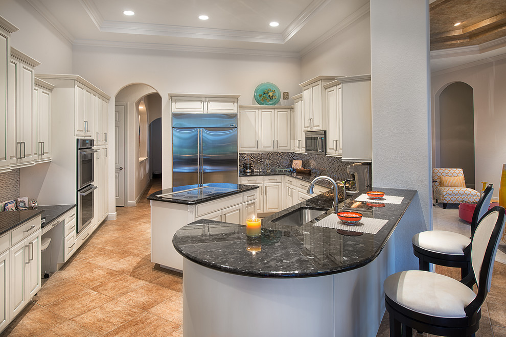 Eat-in kitchen - mid-sized contemporary l-shaped porcelain tile eat-in kitchen idea in Miami with an undermount sink, raised-panel cabinets, white cabinets, granite countertops, multicolored backsplash, mosaic tile backsplash, stainless steel appliances and an island