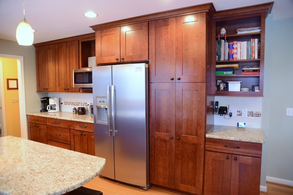 Eat-in kitchen - mid-sized traditional galley light wood floor eat-in kitchen idea in New York with flat-panel cabinets, medium tone wood cabinets, white backsplash, subway tile backsplash, stainless steel appliances and an island