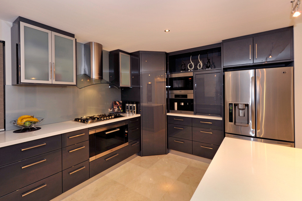 Inredning av ett modernt mellanstort kök, med en undermonterad diskho, släta luckor, bänkskiva i rostfritt stål, grått stänkskydd, glaspanel som stänkskydd, rostfria vitvaror, marmorgolv och en köksö