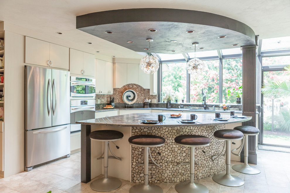 Example of a large minimalist l-shaped limestone floor eat-in kitchen design in Baltimore with an undermount sink, flat-panel cabinets, beige cabinets, multicolored backsplash, mosaic tile backsplash, stainless steel appliances and an island