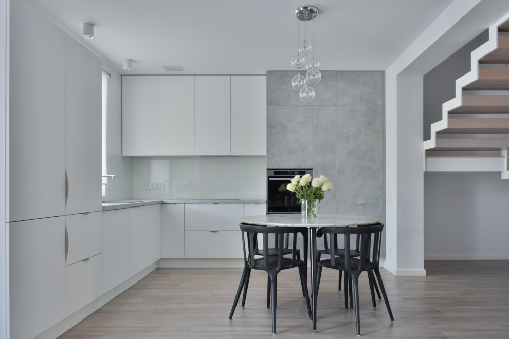 Idéer för att renovera ett mellanstort minimalistiskt grå grått kök, med en enkel diskho, släta luckor, vita skåp, laminatbänkskiva, vitt stänkskydd, glaspanel som stänkskydd, klinkergolv i keramik, integrerade vitvaror och brunt golv