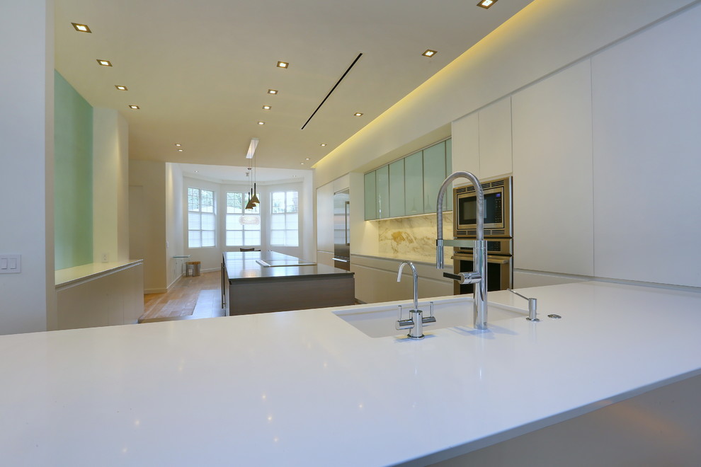 Esempio di una cucina abitabile design con lavello sottopiano, ante lisce, ante bianche, top in quarzite, paraspruzzi bianco, paraspruzzi in lastra di pietra e elettrodomestici in acciaio inossidabile