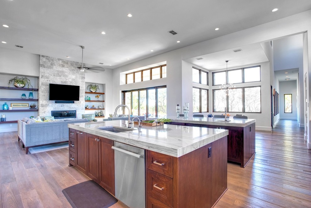 Inspiration for a mid-sized contemporary galley porcelain tile and brown floor open concept kitchen remodel in Austin with a drop-in sink, flat-panel cabinets, white cabinets, marble countertops, beige backsplash, mosaic tile backsplash, stainless steel appliances and two islands