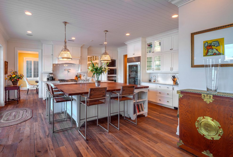 This is an example of a large beach style kitchen in Tampa with shaker cabinets, white cabinets, marble worktops, white splashback, metro tiled splashback, stainless steel appliances, medium hardwood flooring and multiple islands.