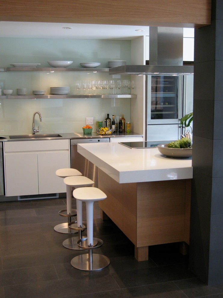 Exempel på ett modernt kök, med en integrerad diskho, släta luckor, bänkskiva i kvarts, vitt stänkskydd, glaspanel som stänkskydd, rostfria vitvaror och en köksö