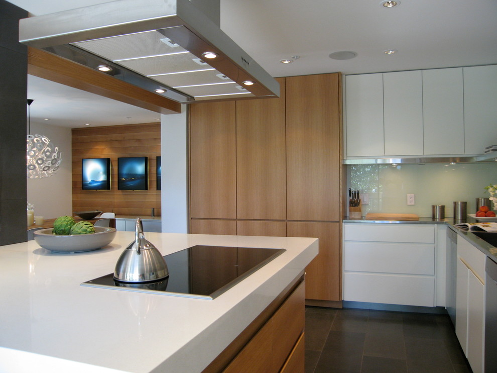 Foto på ett funkis kök, med en integrerad diskho, släta luckor, bänkskiva i kvarts, vitt stänkskydd, glaspanel som stänkskydd, rostfria vitvaror och en köksö