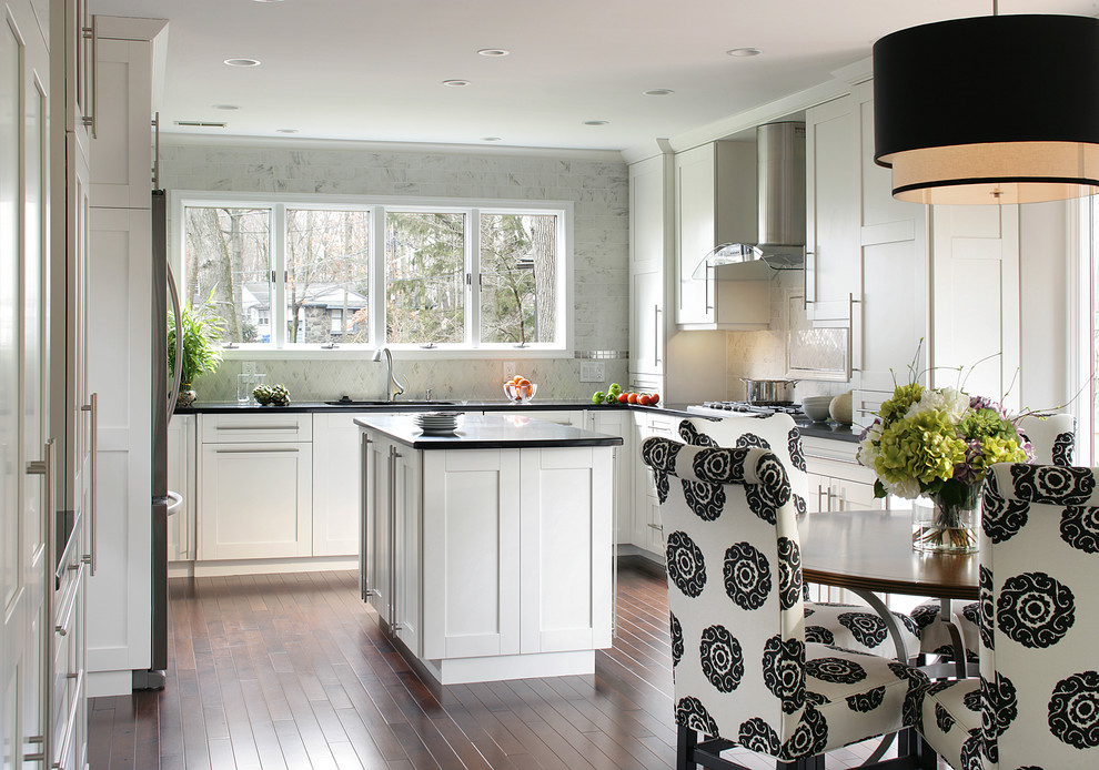 Modern inredning av ett stort kök, med vita skåp, rostfria vitvaror, en dubbel diskho, skåp i shakerstil, granitbänkskiva, vitt stänkskydd, stänkskydd i porslinskakel, mörkt trägolv och en köksö