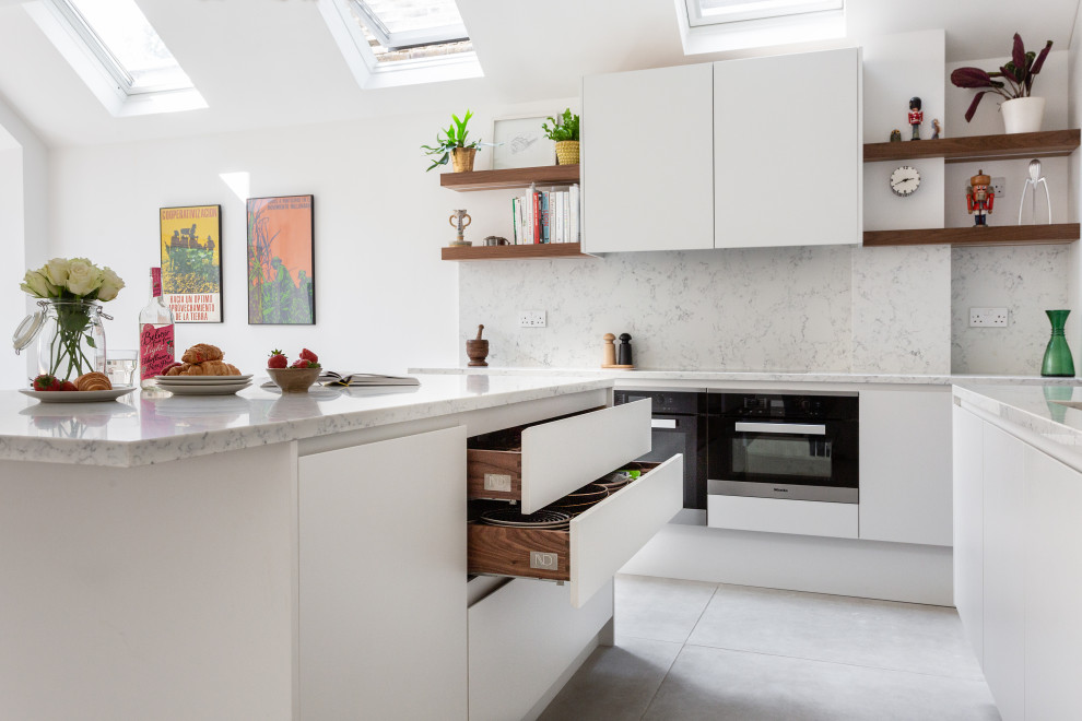 Idéer för ett mellanstort modernt vit kök och matrum, med en nedsänkt diskho, släta luckor, vita skåp, marmorbänkskiva, vitt stänkskydd, stänkskydd i marmor, svarta vitvaror, klinkergolv i keramik, en köksö och vitt golv