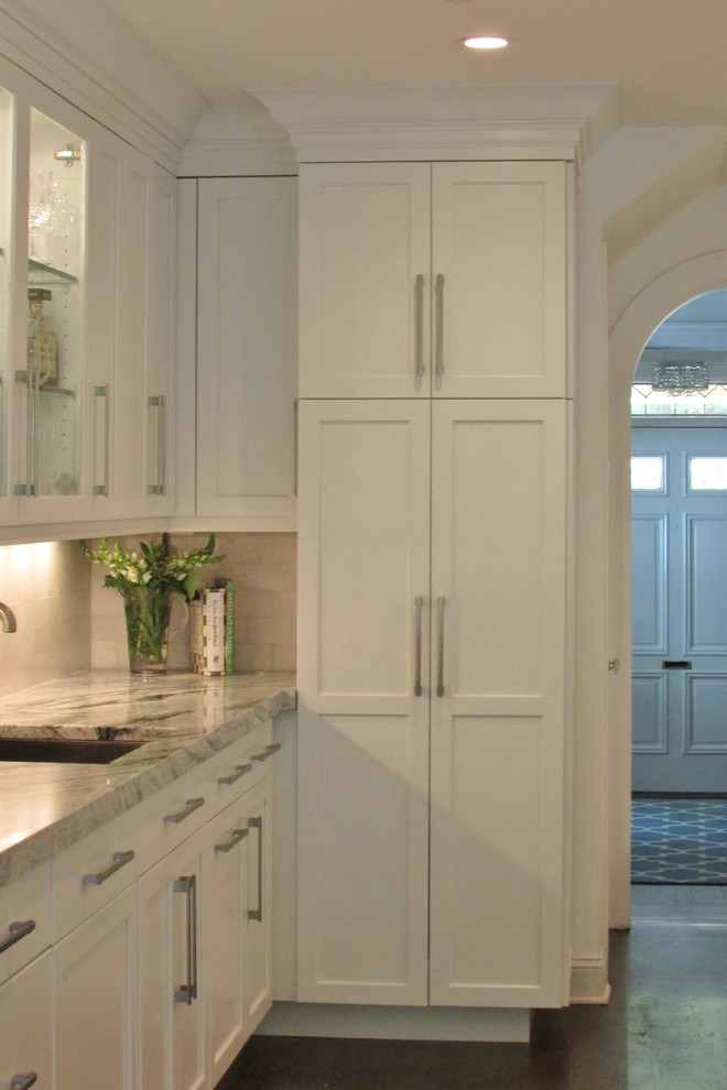 Example of a large transitional l-shaped dark wood floor enclosed kitchen design in New York with white cabinets, white backsplash, stainless steel appliances, an island, a double-bowl sink, shaker cabinets, marble countertops and subway tile backsplash