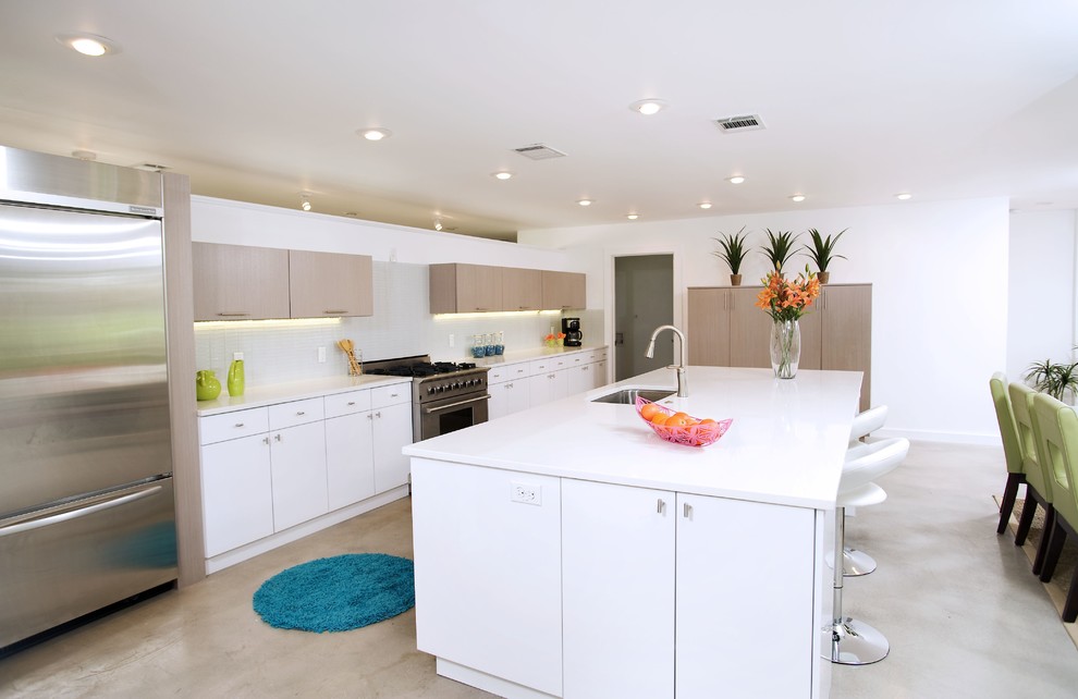 Imagen de cocina comedor contemporánea con armarios con paneles lisos, electrodomésticos de acero inoxidable, puertas de armario blancas y salpicadero blanco