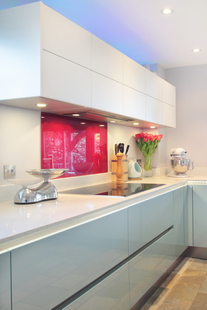 Esempio di una cucina design di medie dimensioni con ante lisce, ante blu, paraspruzzi rosso, paraspruzzi con piastrelle di vetro e elettrodomestici in acciaio inossidabile