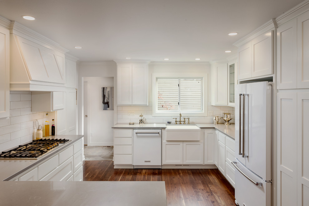 Enclosed kitchen - mid-sized transitional l-shaped dark wood floor and brown floor enclosed kitchen idea in Other with a farmhouse sink, shaker cabinets, white cabinets, solid surface countertops, white backsplash, subway tile backsplash, white appliances and no island