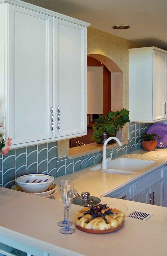 Idéer för att renovera ett avskilt, mellanstort funkis l-kök, med en integrerad diskho, luckor med infälld panel, vita skåp, bänkskiva i koppar, blått stänkskydd, stänkskydd i keramik, vita vitvaror och travertin golv