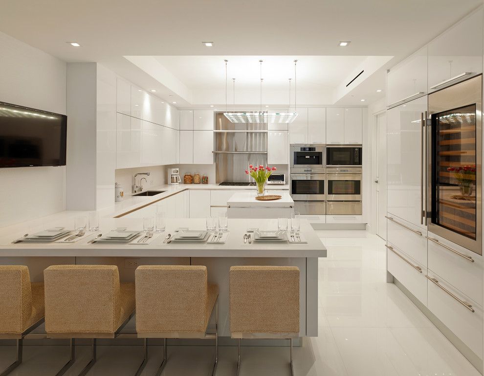 Idée de décoration pour une cuisine ouverte design en U avec un placard à porte plane et des portes de placard blanches.