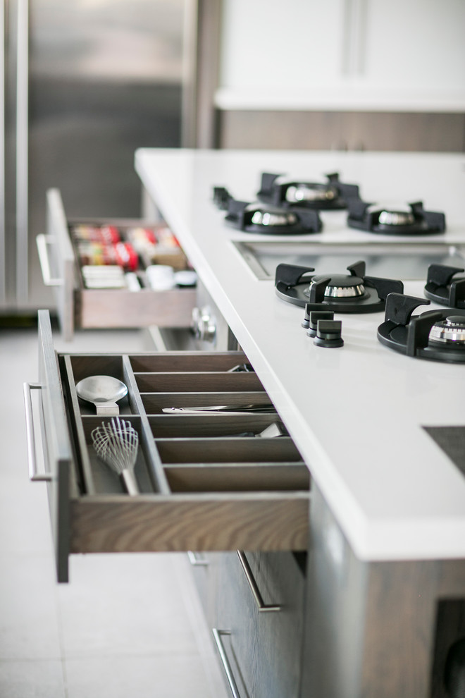 ニューヨークにある高級な広いコンテンポラリースタイルのおしゃれなキッチン (アンダーカウンターシンク、フラットパネル扉のキャビネット、中間色木目調キャビネット、クオーツストーンカウンター、白いキッチンパネル、ガラスタイルのキッチンパネル、シルバーの調理設備、磁器タイルの床) の写真