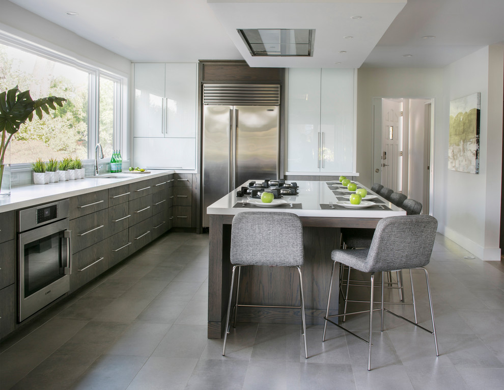 Large contemporary u-shaped kitchen in New York with a submerged sink, flat-panel cabinets, medium wood cabinets, engineered stone countertops, stainless steel appliances, porcelain flooring and an island.