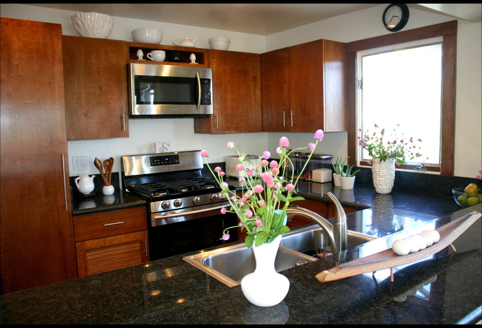 Example of a small trendy galley medium tone wood floor kitchen design in Los Angeles with a drop-in sink, flat-panel cabinets, medium tone wood cabinets, granite countertops, stainless steel appliances and an island