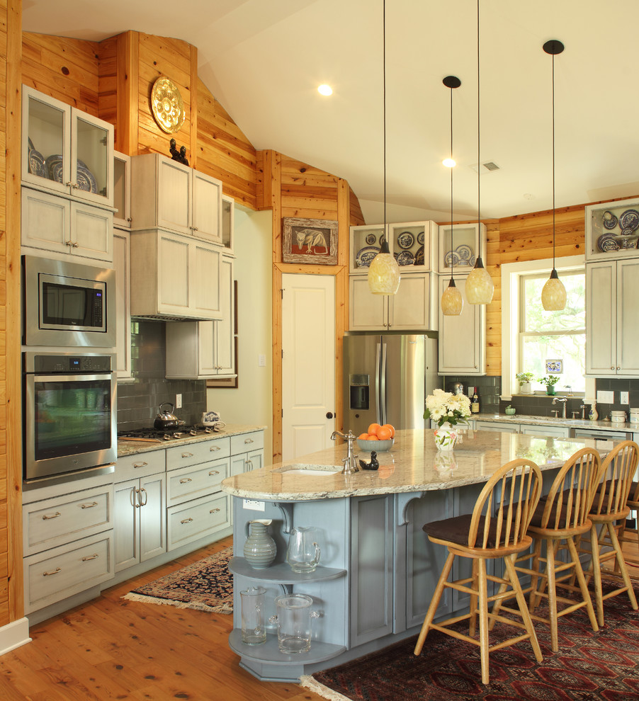 Foto på ett stort rustikt kök med öppen planlösning, med en dubbel diskho, släta luckor, blå skåp, granitbänkskiva, grått stänkskydd, stänkskydd i tunnelbanekakel, rostfria vitvaror, mellanmörkt trägolv och en köksö