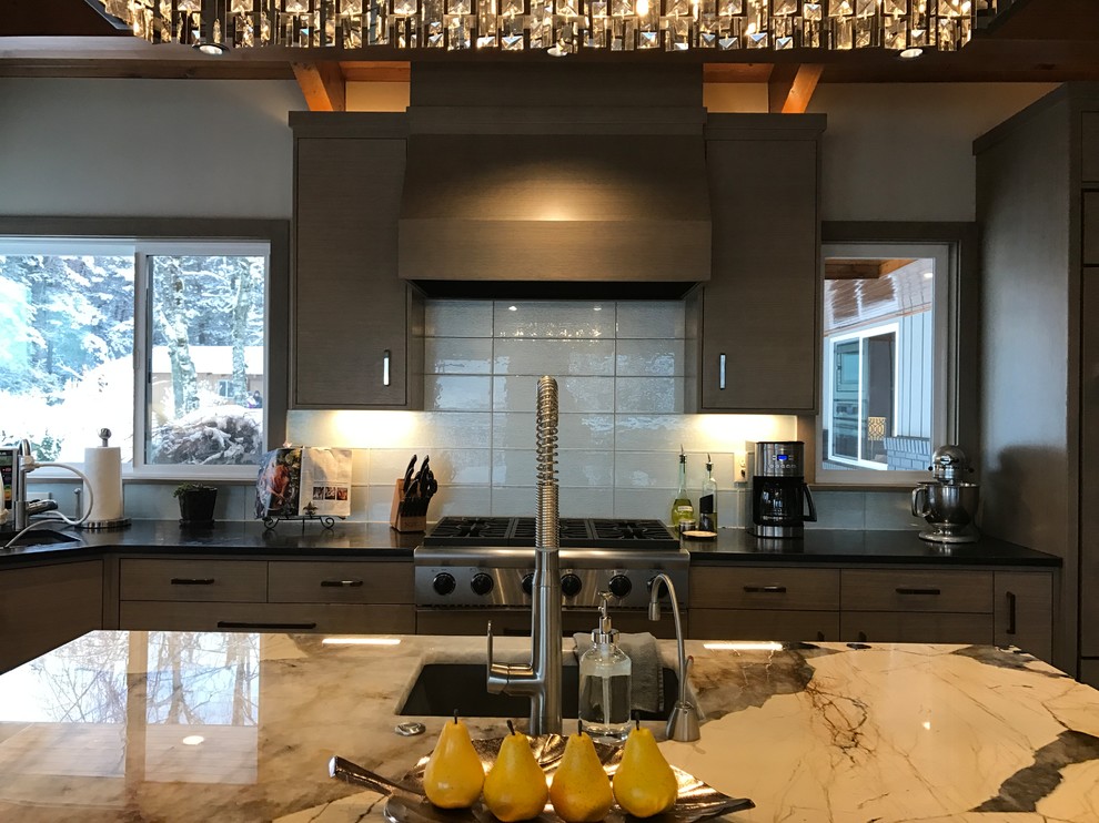 Bild på ett mellanstort retro kök, med en enkel diskho, släta luckor, grå skåp, granitbänkskiva, blått stänkskydd, stänkskydd i glaskakel, integrerade vitvaror, mellanmörkt trägolv och en köksö