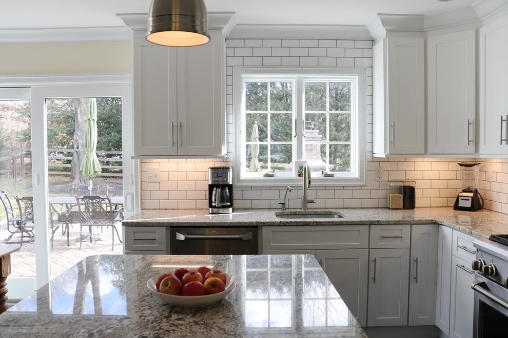 Inspiration for a mid-sized transitional u-shaped porcelain tile and black floor eat-in kitchen remodel in New York with shaker cabinets, white cabinets, granite countertops, white backsplash, an island, an undermount sink, subway tile backsplash and stainless steel appliances