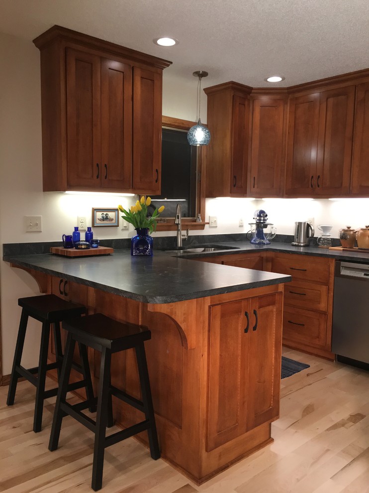 Exempel på ett avskilt, mellanstort klassiskt svart svart u-kök, med en undermonterad diskho, luckor med infälld panel, skåp i mellenmörkt trä, granitbänkskiva, svart stänkskydd, stänkskydd i sten, rostfria vitvaror, ljust trägolv, en halv köksö och beiget golv