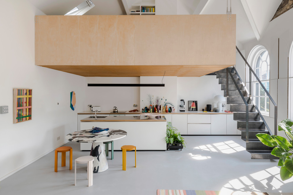 Inspiration for a contemporary galley open plan kitchen in London with flat-panel cabinets, white cabinets, concrete flooring, an island and grey floors.