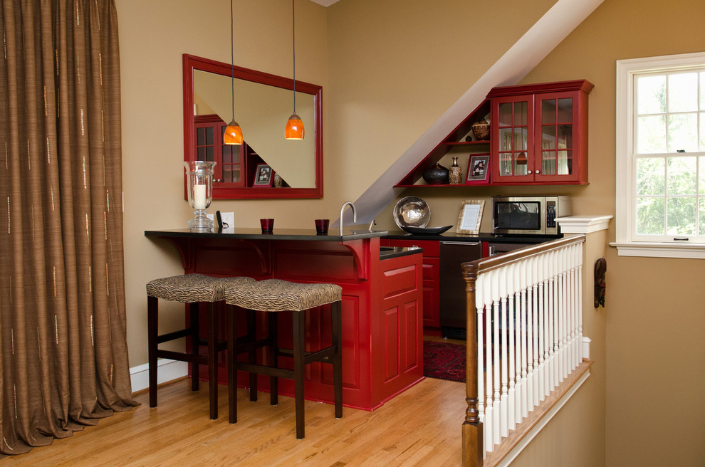 На фото: маленькая кухня-гостиная с врезной мойкой, красными фасадами, техникой из нержавеющей стали, паркетным полом среднего тона и островом для на участке и в саду