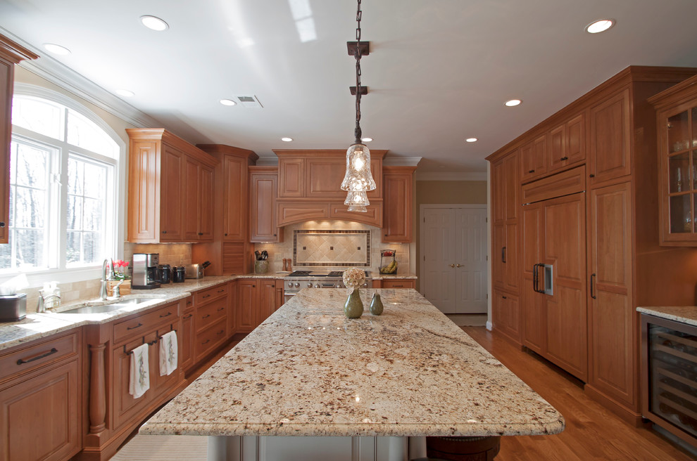 Exempel på ett klassiskt kök, med en dubbel diskho, luckor med upphöjd panel, skåp i mellenmörkt trä, granitbänkskiva, beige stänkskydd och integrerade vitvaror