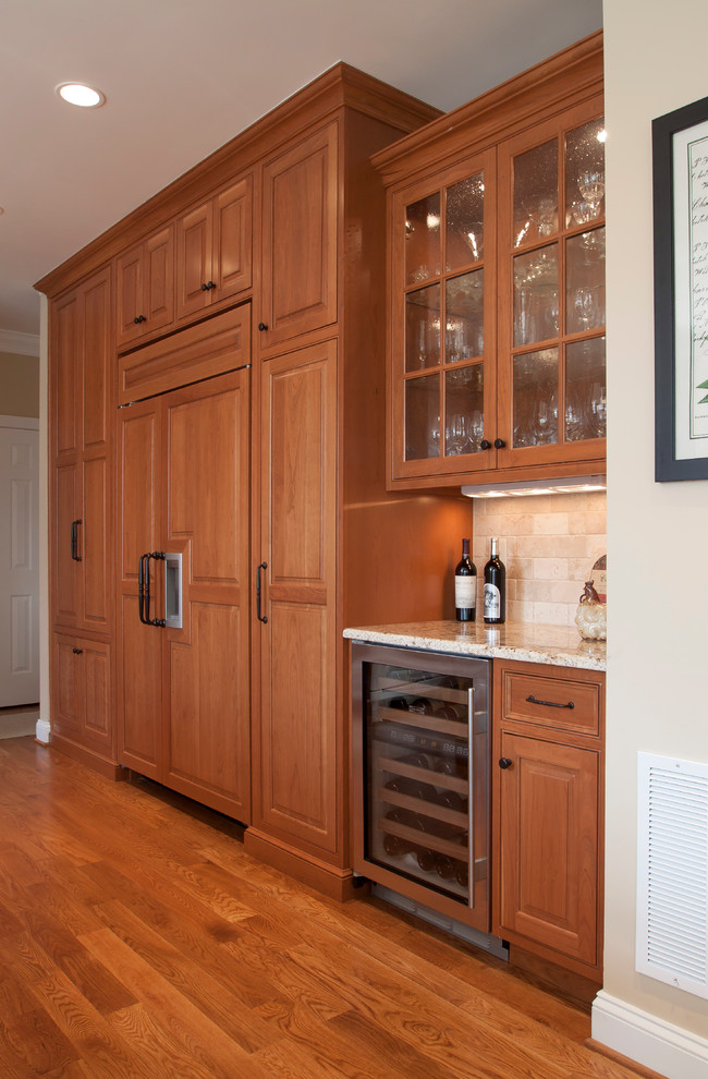 Cette image montre une cuisine encastrable traditionnelle en bois brun avec un placard à porte affleurante, un plan de travail en granite et une crédence beige.