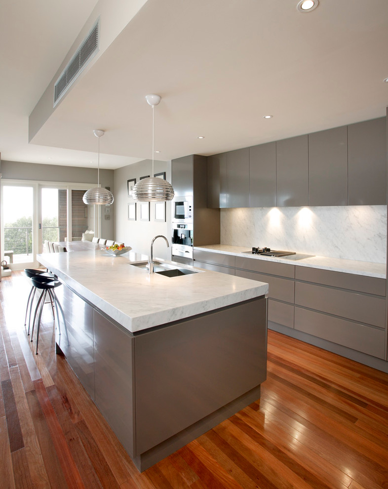 Design ideas for a medium sized contemporary l-shaped open plan kitchen in Sydney with a submerged sink, flat-panel cabinets, beige cabinets, marble worktops, white splashback, stone slab splashback, stainless steel appliances, medium hardwood flooring and an island.