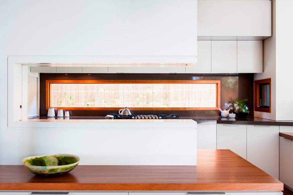 Cette photo montre une cuisine tendance avec des portes de placard blanches, une crédence marron et îlot.