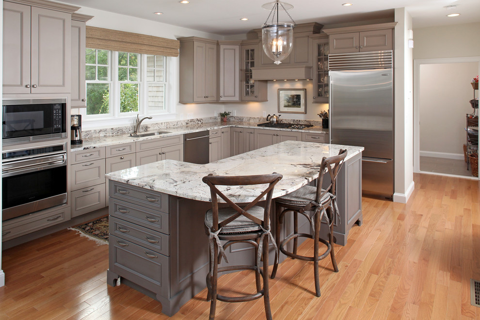 Mid-sized transitional l-shaped medium tone wood floor open concept kitchen photo in Boston with an undermount sink, recessed-panel cabinets, gray cabinets, granite countertops, stainless steel appliances and an island