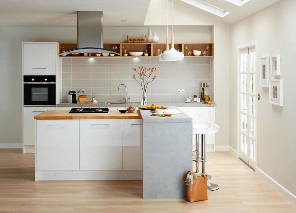 Modern inredning av ett stort linjärt kök och matrum, med släta luckor, vita skåp, grått stänkskydd, svarta vitvaror och en köksö