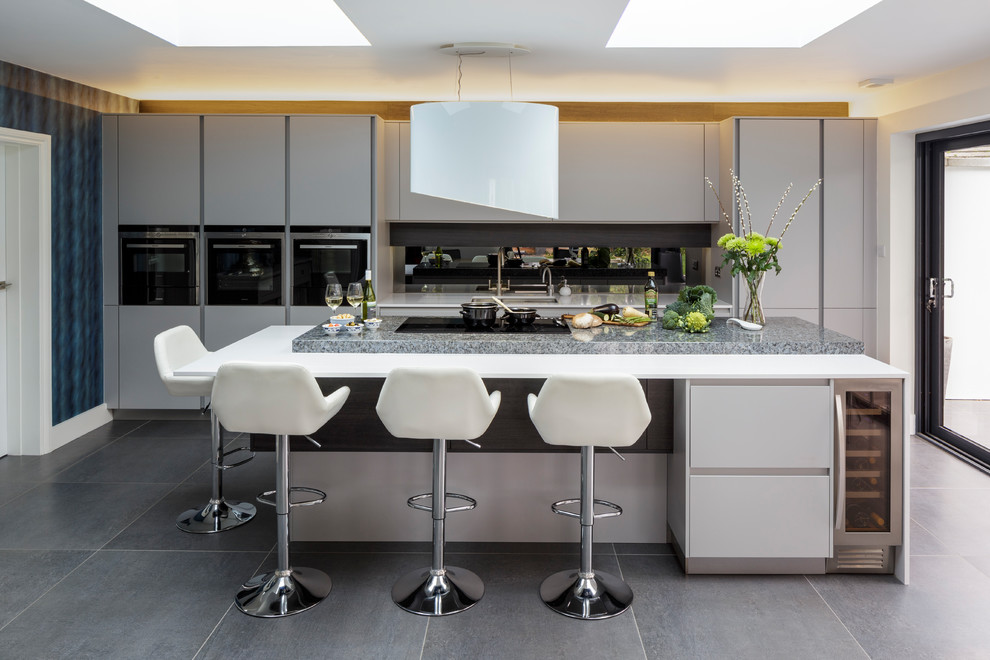 Cette image montre une cuisine américaine design avec îlot, un plan de travail en granite et une crédence grise.