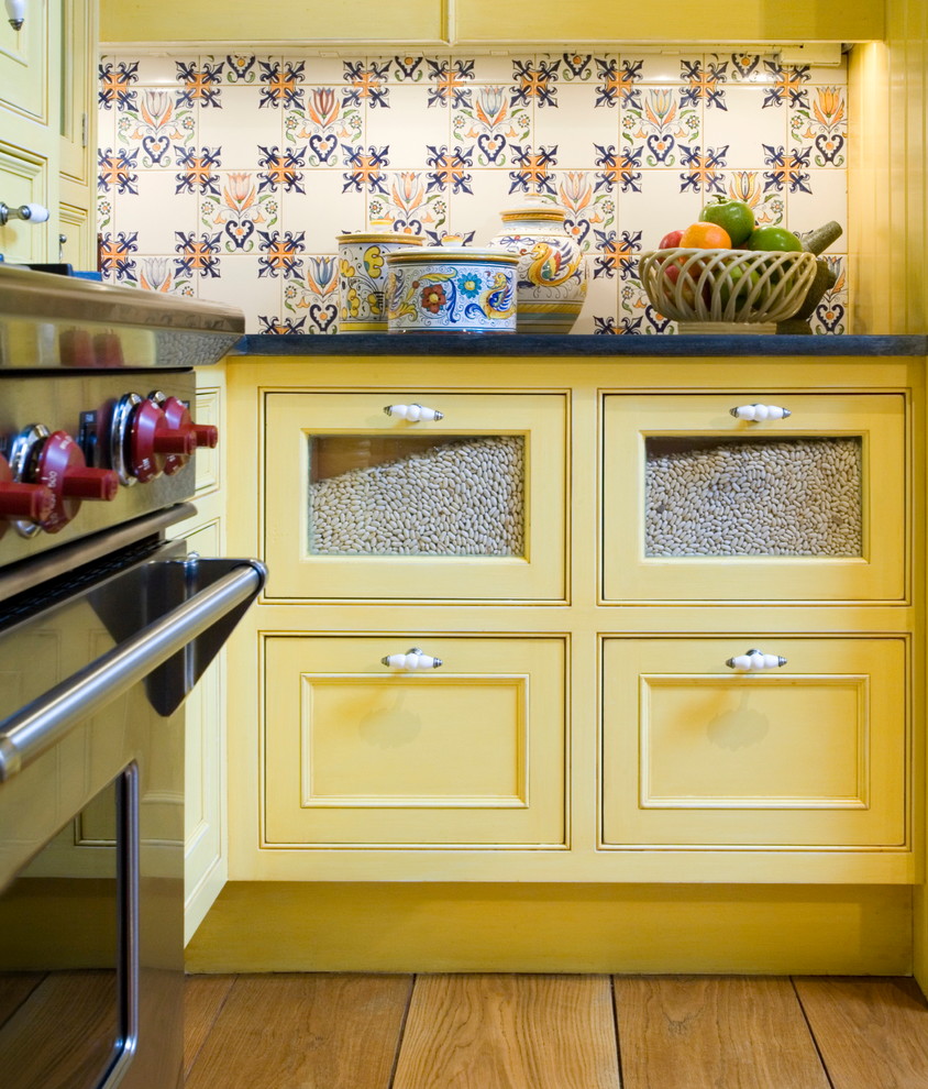 Inspiration for a large timeless u-shaped medium tone wood floor eat-in kitchen remodel in Boston with an island, beaded inset cabinets, yellow cabinets, soapstone countertops, multicolored backsplash, ceramic backsplash, colored appliances and a farmhouse sink