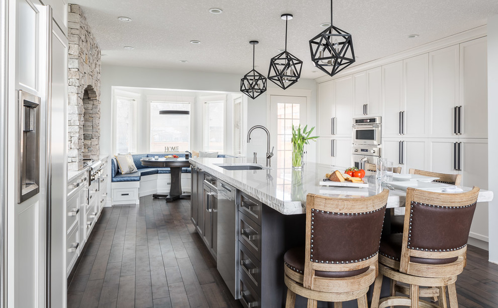 Inspiration for a large traditional kitchen/diner in Calgary with a submerged sink, shaker cabinets, white cabinets, quartz worktops, beige splashback, stone tiled splashback, stainless steel appliances, dark hardwood flooring, an island and brown floors.