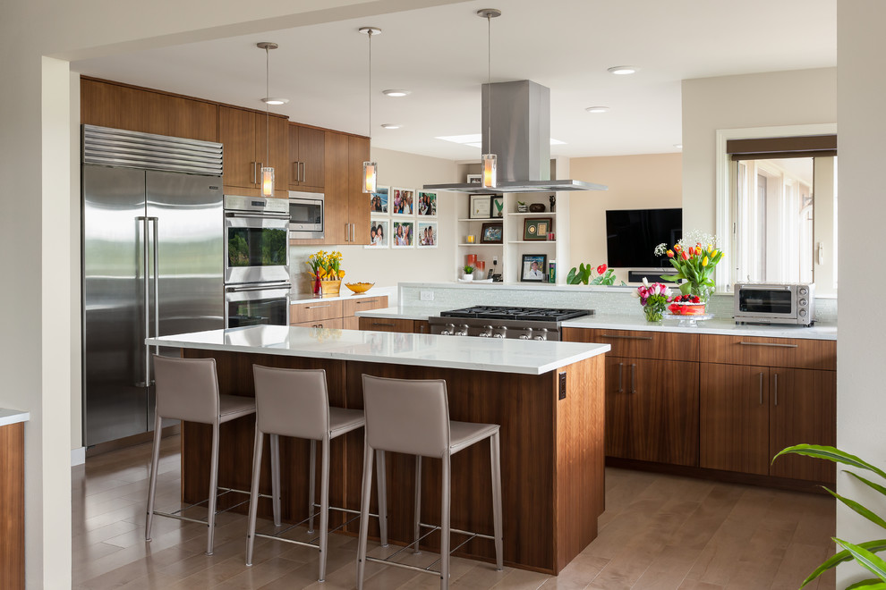 Offene Moderne Küche in L-Form mit flächenbündigen Schrankfronten, hellbraunen Holzschränken, braunem Holzboden, Kücheninsel, braunem Boden und weißer Arbeitsplatte in Seattle