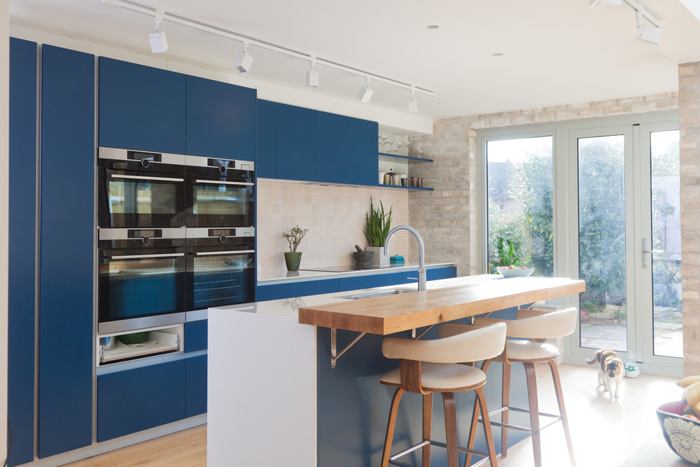 Esempio di una cucina contemporanea di medie dimensioni con lavello a doppia vasca, ante lisce, ante blu, paraspruzzi beige, paraspruzzi con piastrelle in ceramica, elettrodomestici da incasso, pavimento in legno massello medio e pavimento beige