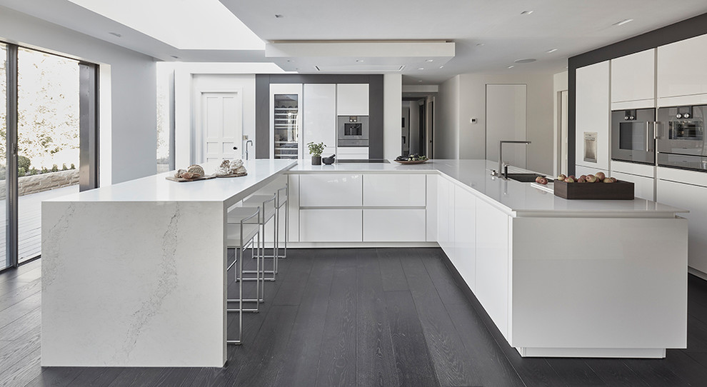 Exempel på ett stort modernt kök, med släta luckor, vita skåp, granitbänkskiva, integrerade vitvaror, mörkt trägolv, en köksö och svart golv